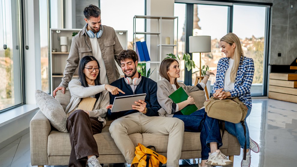Group of diverse young adults are studying and collaborating together, using a digital tablet for their university project